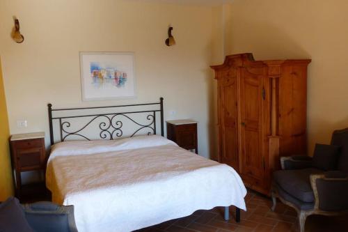 1 dormitorio con 1 cama, armario y silla en Casa romantica in un borgo antico in Sabina, en Cicignano