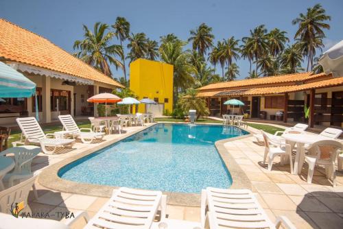 a swimming pool with chairs and umbrellas at a resort at Pousada Yapara-Tyba in Japaratinga