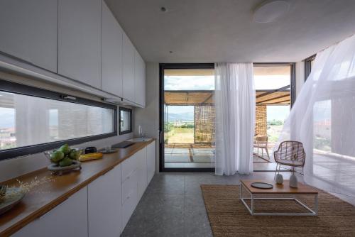 a kitchen with white cabinets and a table and a window at Bouca Houses in Messini