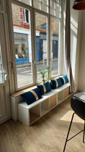a window seat with blue pillows in front of a window at Louisa in Dinard