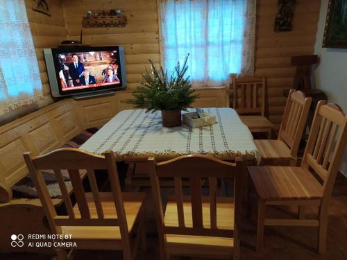 einen Esstisch und Stühle mit einem TV in einer Hütte in der Unterkunft Chata U Juraja in Hruštín