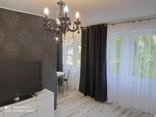 a living room with a television and a chandelier at Apartament Lux2 Konin NOCLEGI in Konin
