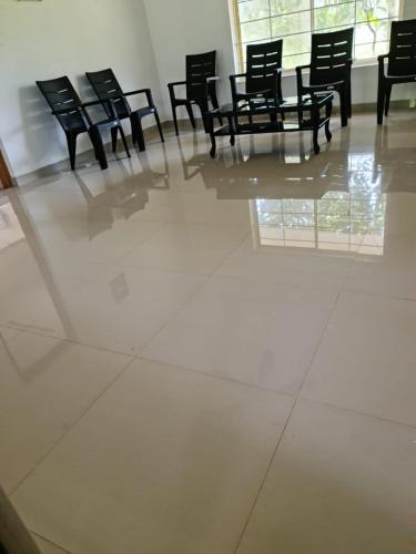 a room with black chairs and a white tile floor at 3R Residency The Backpackers Hub Munnar in Munnar