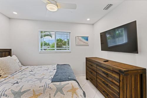 a bedroom with a bed and a flat screen tv at Cinderella's Beach Cottage in North Palm Beach