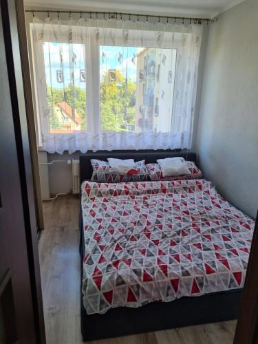 a bedroom with a bed with a comforter and a window at Apartament u Maryśki in Karpacz