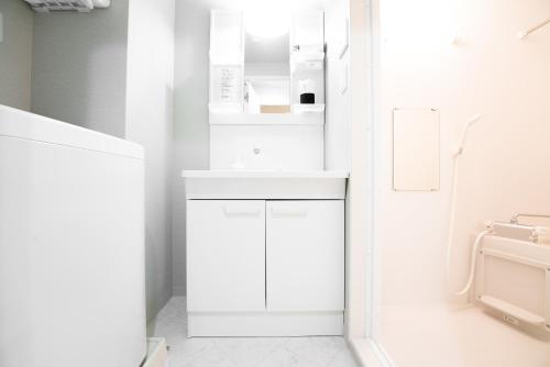 a white bathroom with a sink and a toilet at GN98 Saiwaicho Osaka in Osaka