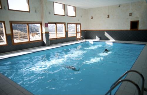 a large swimming pool with a person swimming in it at Appartement 2/4 pers, Résidence 4* Les Hauts de Valmeinier, Centre station in Valmeinier