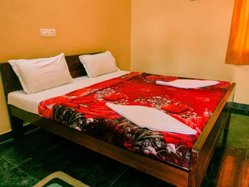 a bed with red sheets and white pillows on it at Srinivasa Residency in Mahabalipuram