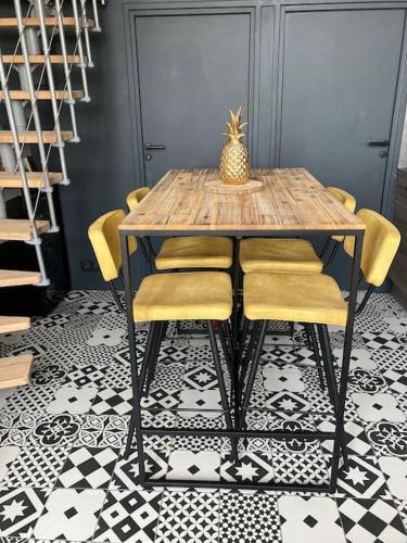 d'une table à manger avec des chaises jaunes et un ananas. dans l'établissement Appartement FACE MER accès direct plage, à Houlgate