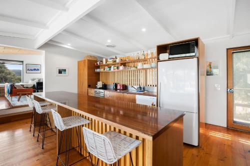 a kitchen with a bar with chairs and a refrigerator at Moggs Magic in Aireys Inlet