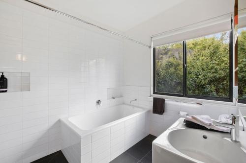 a white bathroom with a tub and a window at Moggs Magic in Aireys Inlet