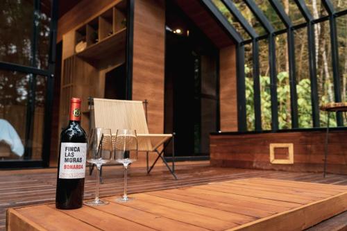 a bottle of wine sitting on a table with two wine glasses at Oculto refugio de bosque in Envigado