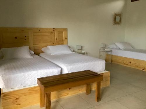a bedroom with two beds and a bench in it at Hotel Indalo adults only in Puerto Viejo