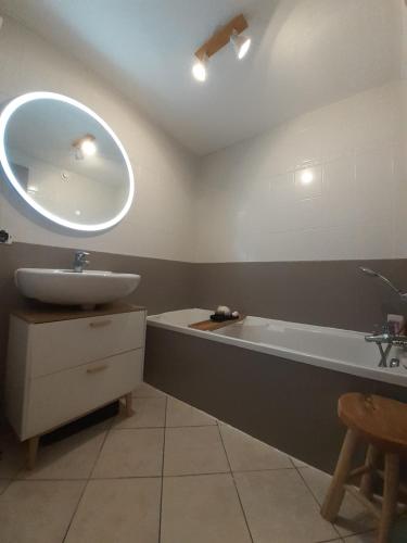 La salle de bains est pourvue d'un lavabo, d'une baignoire et d'un miroir. dans l'établissement Le Pinaud, à Épinal