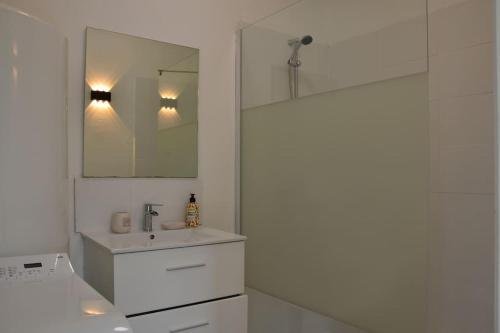 a white bathroom with a sink and a mirror at Gîte de la gare - avec parking in Hesdigneul-lès-Boulogne