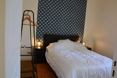 a bedroom with a white bed with a blue wall at Gîte de la gare - avec parking in Hesdigneul-lès-Boulogne