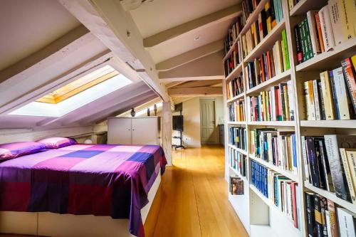 ein Schlafzimmer mit einem Bett und Bücherregalen mit Büchern in der Unterkunft Elkano Room in San Sebastián