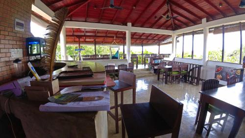 a dining room with tables and chairs and windows at Fort Dew Guest House in Galle