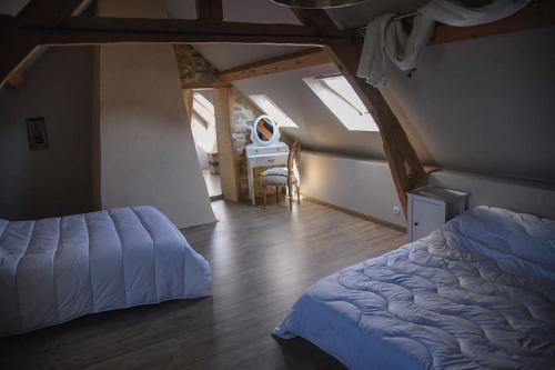 ein Schlafzimmer mit einem Bett und einem Tisch im Dachgeschoss in der Unterkunft Gîte de la bergerie côte d'Opale in Souverain-Moulin