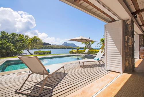 Una terraza con dos sillas y una piscina. en Villa Fauverelle, en Mahébourg