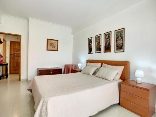 O Cantinho do Algarve في بورش: غرفة نوم بيضاء بسرير وصورتين على الحائط