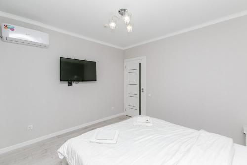 um quarto branco com uma cama e uma televisão de ecrã plano em Apartament in zona Centrala si Parc em Chisinau