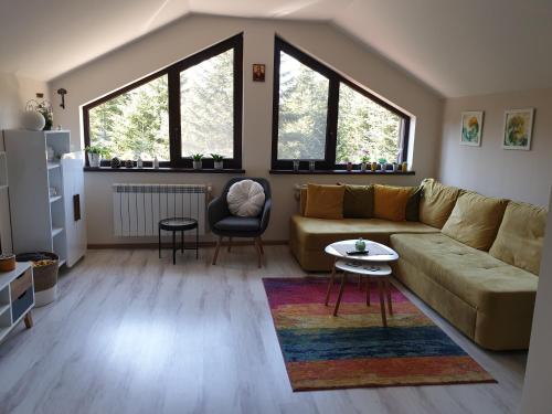a living room with a couch and two windows at Borovets Cozy Mountain Apartments in Borovets