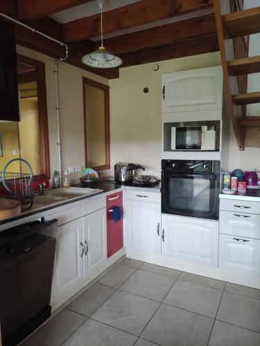 a kitchen with white cabinets and a stove top oven at Gîte de la Forêt in Saint-Jeanvrin