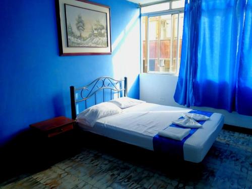 Dormitorio azul con cama y ventana en Hostal El Rey, en Buenaventura