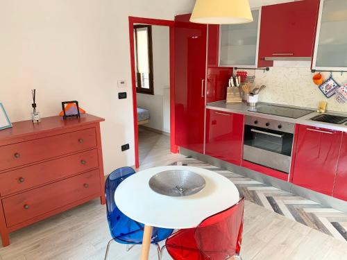 パドヴァにあるLa Bohemeのキッチン(赤いキャビネット、白いテーブルとスツール付)