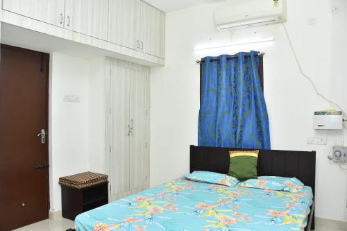 a bedroom with a bed and a blue curtain at Mahabs homestay Villa in Mahabalipuram
