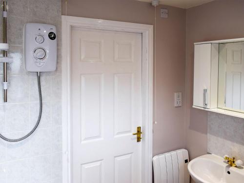 La salle de bains est pourvue d'une douche et d'une porte blanche. dans l'établissement Moordale Cottage, à Reeth