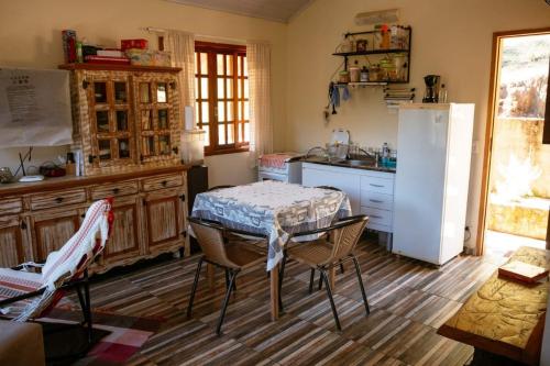 a kitchen with a table and a refrigerator at Chalé da Mata in Sapucaí-Mirim