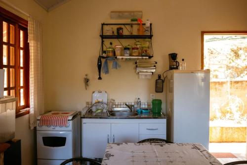 a small kitchen with a sink and a refrigerator at Chalé da Mata in Sapucaí-Mirim
