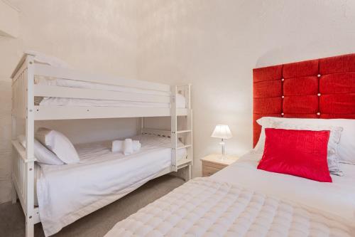 a bedroom with two bunk beds and a red headboard at Cottage 3 Old Farmhouse Mews in Keswick