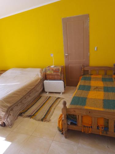 a bedroom with two beds and a yellow wall at Laprida in Ramallo