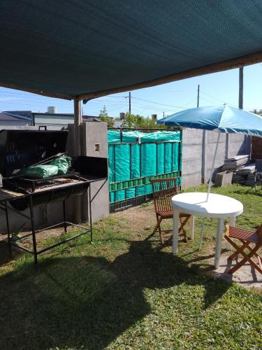 a grill and a table and an umbrella in a yard at Laprida in Ramallo