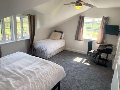 a bedroom with two beds and a desk and windows at Ranch House in Preesall