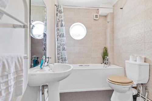 a bathroom with a toilet and a tub and a sink at The Old Brewery House - By My Getaways - Free Parking in Brighton & Hove