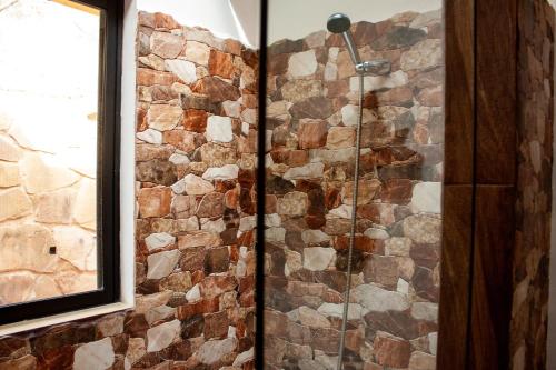 a glass shower in a bathroom with a stone wall at Cabaña Los Guapurús in Samaipata