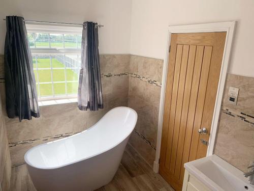 a bathroom with a tub and a sink and a window at Ranch House in Preesall