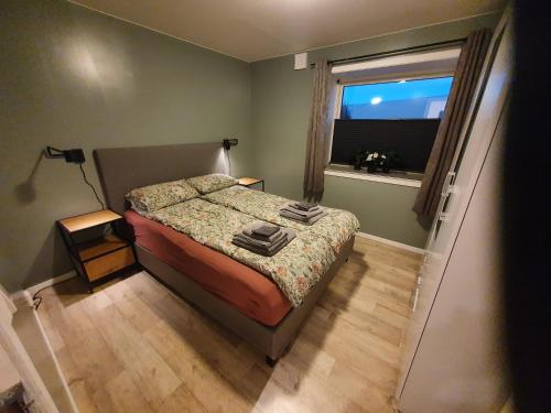 a small bedroom with a bed and a window at Åsveien Apartments. in Harstad