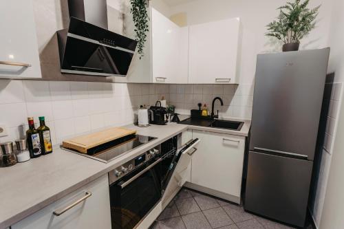 uma cozinha com armários brancos e um frigorífico de aço inoxidável em Stilvolle, gemütliche Wohnung mitten im ZENTRUM em Leipzig