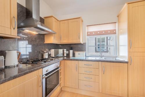 a kitchen with wooden cabinets and a stove top oven at Cottage 9 Old Farmhouse Braithwaite in Keswick