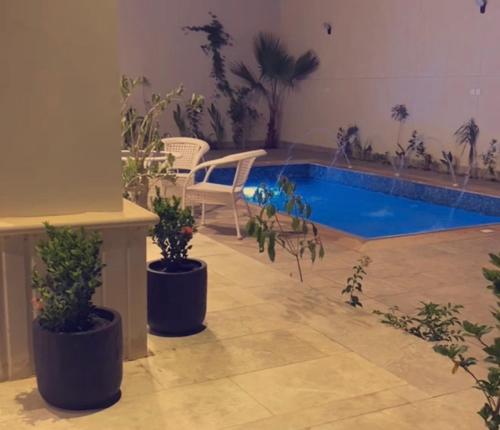 a swimming pool in a room with potted plants at منتجع سورا in Buraydah