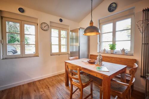 a dining room with a wooden table and two windows at Ferienhaus Asten-Lodge in Winterberg