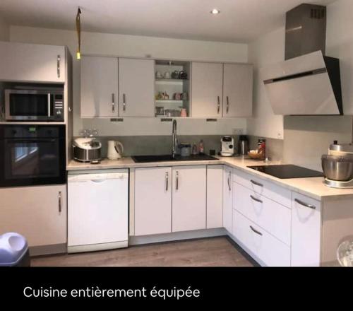 una cucina bianca con armadietti e elettrodomestici bianchi di Cosy Maison LOURDES a Lourdes
