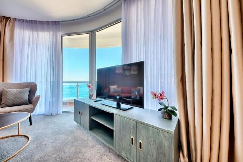 a living room with a television and a couch and a chair at Kalamper Hotel & Spa in Dobra Voda