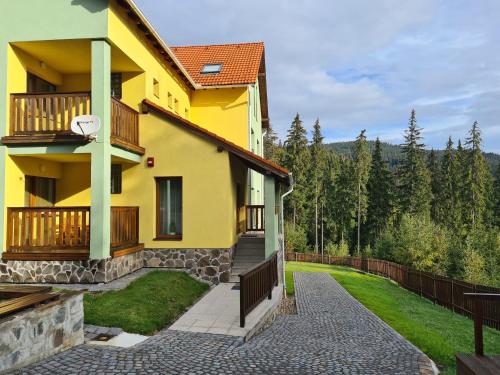 ein gelbes Haus mit einem Balkon und einem Gehweg in der Unterkunft casaafina in Harghita-Băi