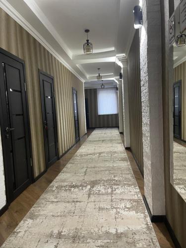 a hallway with black doors and a rug on the floor at Роща 7 in Bishkek